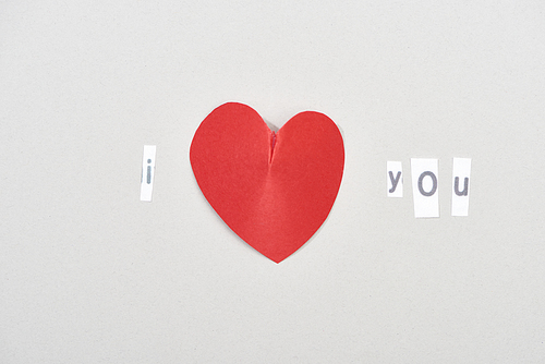 Top view of i love you lettering with heart shaped paper on grey background