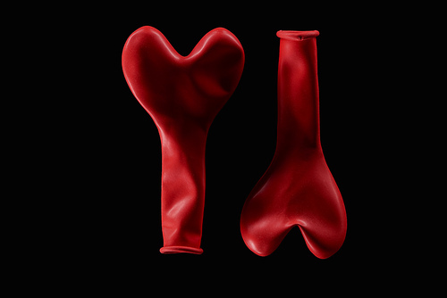 Top view of two red balloons in heart shape isolated on black