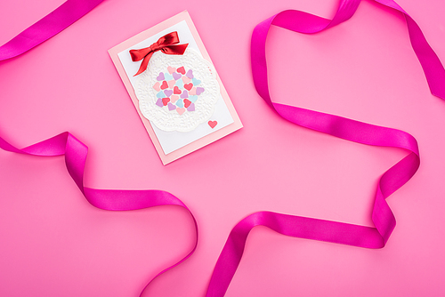 top view of valentines greeting card with ribbon isolated on pink