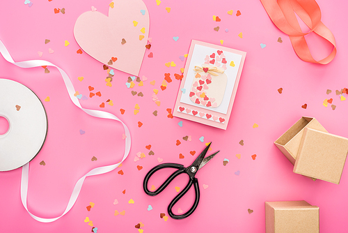top view of valentines confetti, empty compact disk, scissors, gift boxes, greeting card on pink background