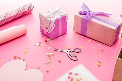 valentines confetti, scissors, wrapping paper, gift boxes on pink background