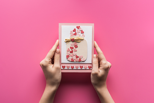 cropped view of woman holding valentines greeting card isolated on pink