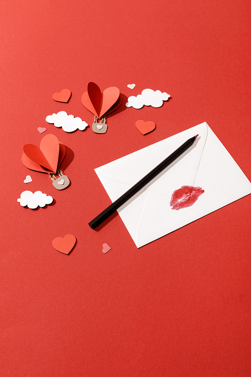 paper clouds and heart shaped air balloons, envelope with lip  and pencil on red background