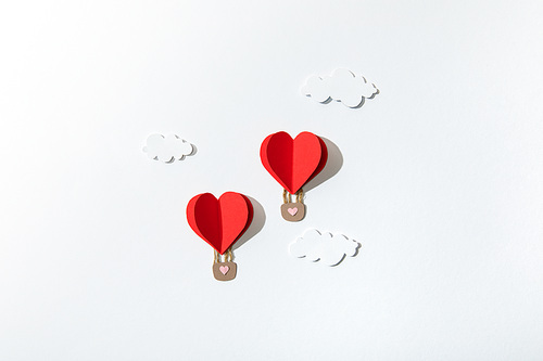 top view of paper heart shaped air balloons in clouds on white background