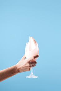 cropped view of woman holding glass with fresh pink milk splash isolated on blue