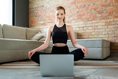 happy sportswoman watching online exercise on laptop in living room