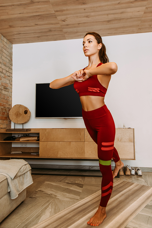 attractive sportswoman training online with resistance band on fitness mat at home during self isolation