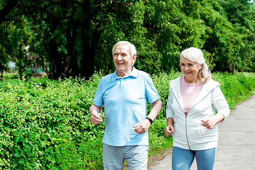 cheerful senior man running near wife in park