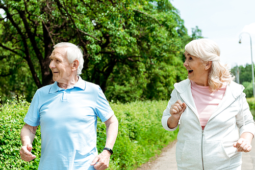 happy senior man and retired woman running in park