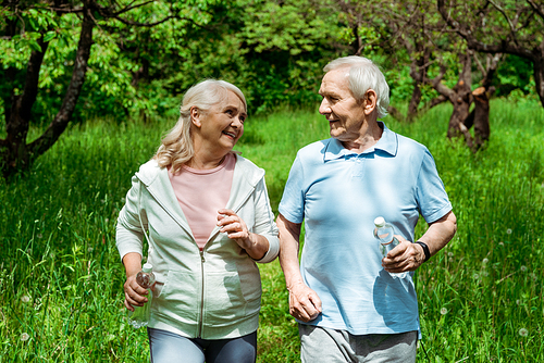 senior woman looking at husband with grey hair while running in green park