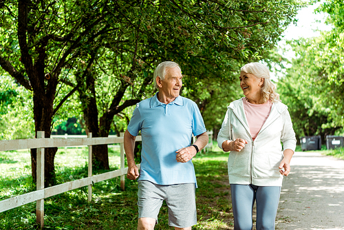 happy retired woman running near senior husband in park