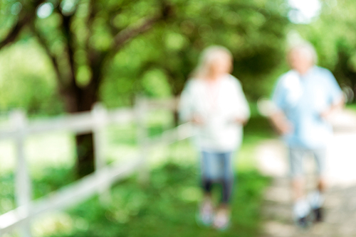 blurred view of retired woman running near senior man in park