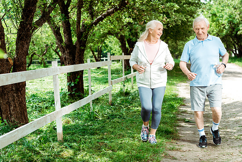 cheerful retired man running near senior wife in park