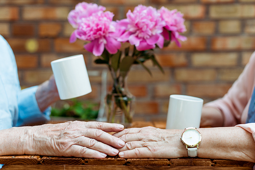 cropped view of senior man touching hand of retired woman