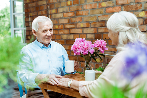 selective focus of senior man touching hand of retired woman