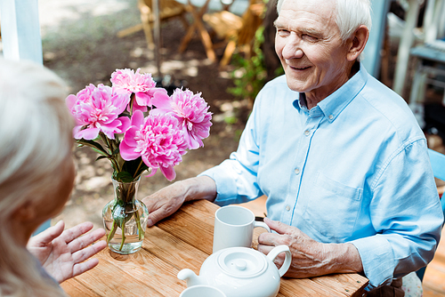 selective focus of happy senior man holding cup and looking at wife