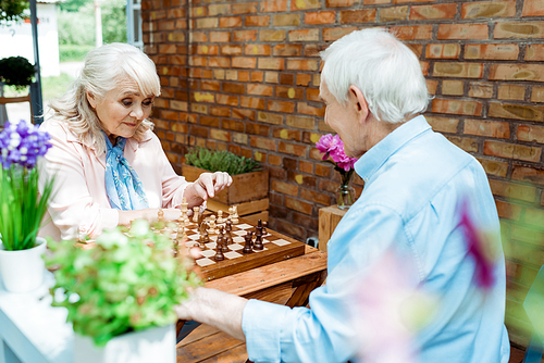 selective focus of retired man and woman playing chess