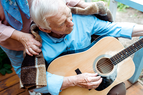 cropped view of senior woman near husband playing acoustic guitar