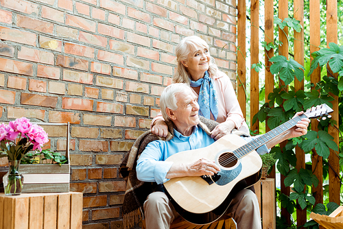 low angle view of retired husband playing acoustic guitar near happy wife