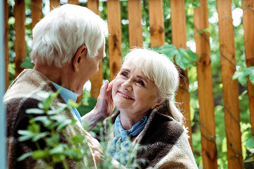 selective focus of senior man with grey hair touching face of retired wife