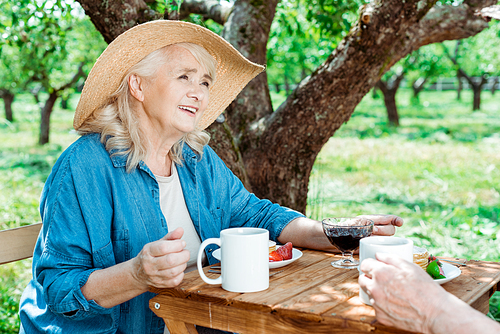 cropped view of senior man near retired woman in straw hat