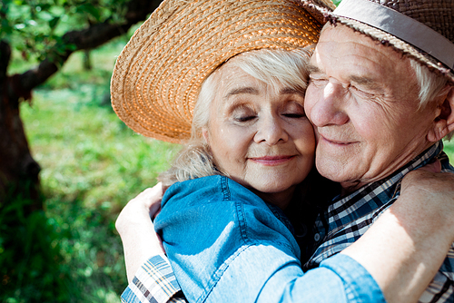 cheerful senior woman hugging happy retired husband with closed eyes