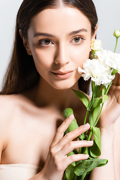 beautiful brunette woman with white carnations looking away isolated on grey