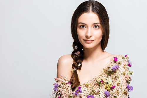 beautiful young woman with braid in mesh with spring wildflowers isolated on grey