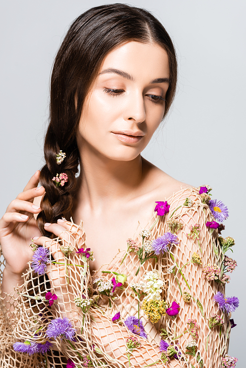 beautiful woman with braid in mesh with spring wildflowers isolated on grey