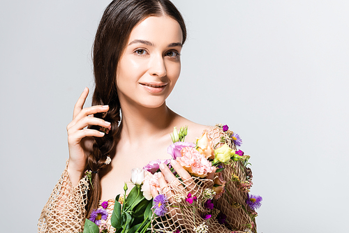 smiling beautiful woman with braid in mesh with spring wildflowers isolated on grey