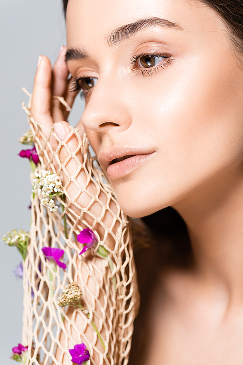 portrait of beautiful woman in mesh with purple flowers isolated on grey