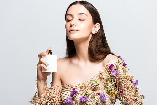beautiful woman in mesh clothing with purple flowers spraying perfume with floral scent on skin isolated on grey