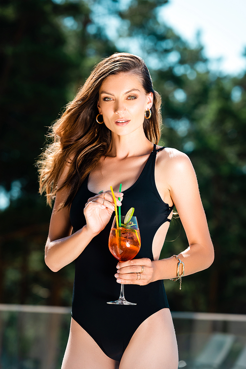 attractive sexy woman in swimming suit posing with cocktail on resort