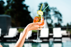 Cropped view of woman holding cocktail with mint and lemon on resort