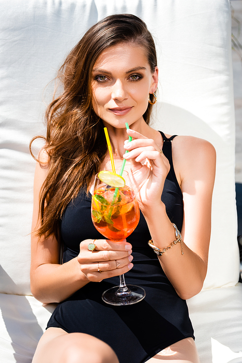 attractive woman in swimming suit on sunbed with cocktail on resort