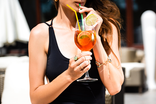 partial view of girl in swimming suit drinking cocktail on resort