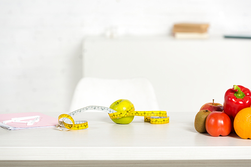 folder, measure tape and fresh fruits and vegetables on table