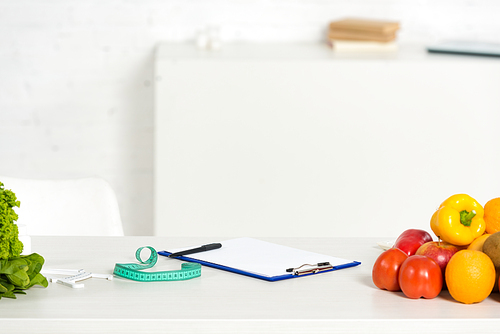 clipboard with pen, measure tape and fresh fruits and vegetables on table