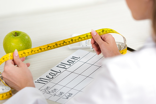 cropped view of dietitian holding measure tape at workplace