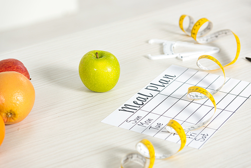meal plan, caliper, measure tape and fresh fruits on table
