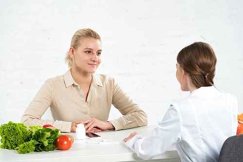 dietitian in white coat and patient looking at each other at table