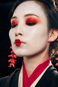 low angle view of beautiful geisha with red eyeshadow and lips isolated on black
