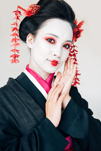cheerful beautiful geisha in black kimono with red flowers in hair isolated on white