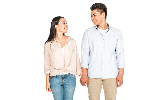 happy asian couple holding hands and looking at each other isolated on white