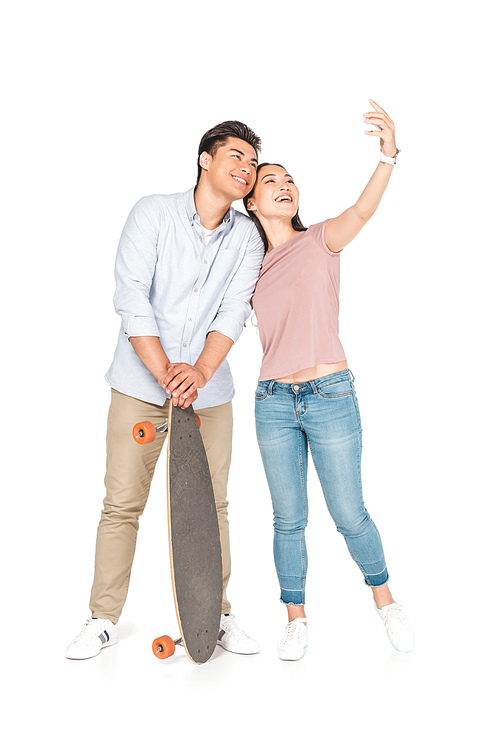 happy asian girl taking selfie with handsome boyfriend holding longboard on white background