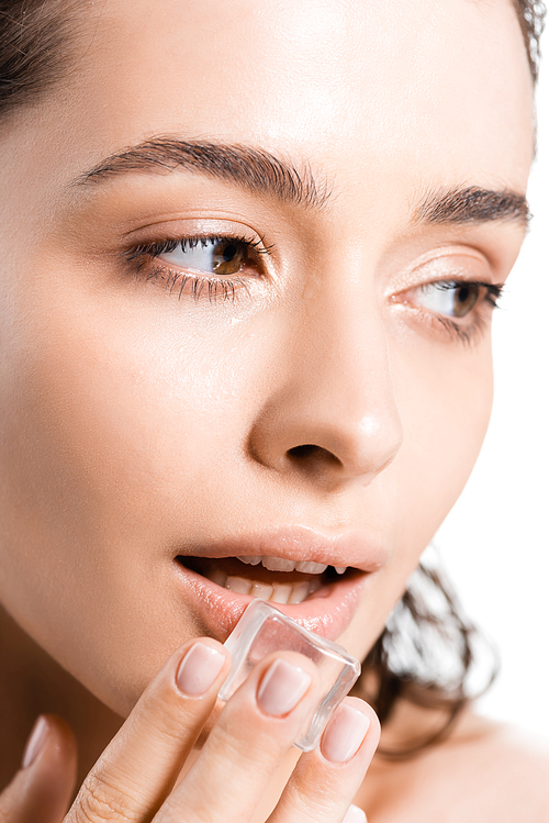 유토이미지 | portrait of brunette young woman holding ice cube near lips and looking away isolated on white