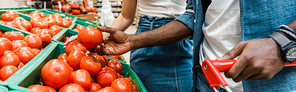 panoramic shot of african american man holding fresh tomato near girl in supermarket