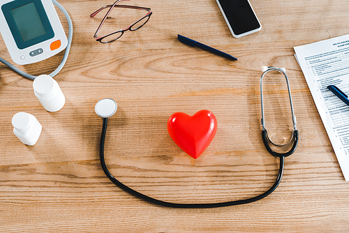 top view of stethoscope near red heart model and smartphone with blank screen