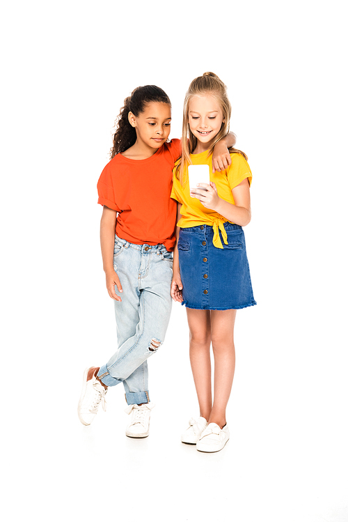 full length view of cute african american kid hugging friend using smartphone on white background