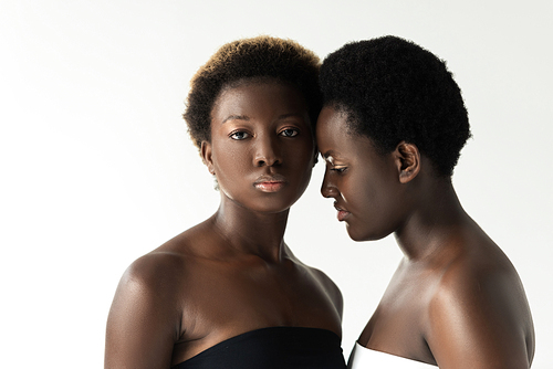 african american women in tops touching foreheads isolated on grey